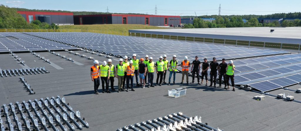 Flera personer i arbetskläder på tak med solpaneler