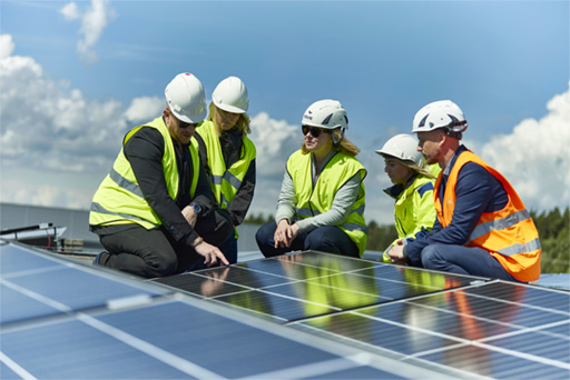 Personer i arbetskläder sitter på tak klätt med solpaneler